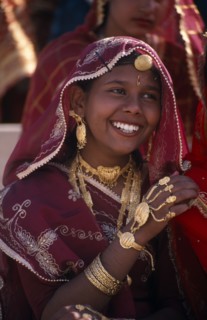 INDIA, Rajasthan, Bikaner, Portrait of a young girl dancer smiling wearing traditional jewellery at