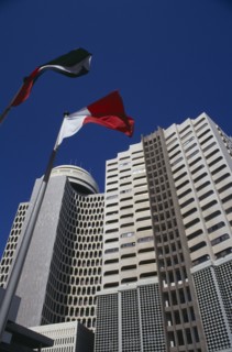 UAE, Dubai , Deira Tower.  Looking up at high rise building with flags flying in foreground.