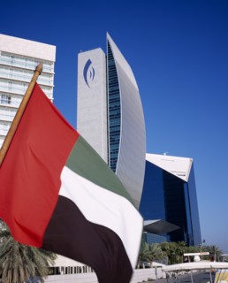 UAE, Dubai, National Bank of Dubai seen from dhow on Dubai creek with UAE flag in the foreground.