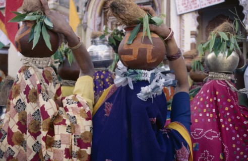 INDIA, Madhya Pradesh, Orccha, Back view of crowd of women carrying metal and earthenware pots on
