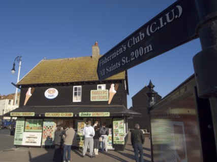 ENGLAND, East Sussex, Hastings, Customers queuing at a seaside take away. A sign with directions to