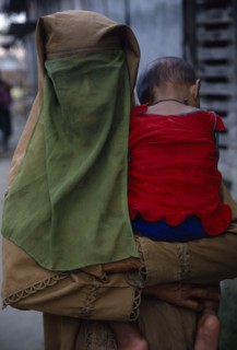 BANGLADESH, Khulna, Char Kukuri Mukuri, Muslim woman wearing full veil and carrying baby against