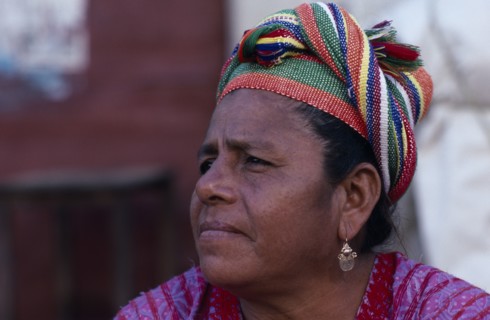 MEXICO, Oaxaca, Juchitan, Head and shoulders portrait of woman wearing coloured headscarf and gold