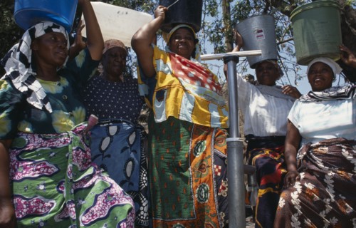 20088822 TANZANIA  Shinyanga Women at standpipe carrying pails of clean water on their heads.  Following 1994 cholera outbreak an urban health programme was set up to teach health awareness.