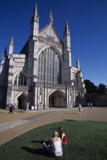 ENGLAND, Hampshire, Winchester, Winchester Cathedral exterior seen from the gardens with two girls