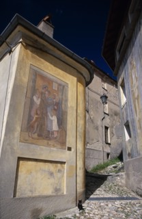 ITALY, Lombardy, Arcumeggia, Narrow cobbled street with fresco decoration on exterior wall of