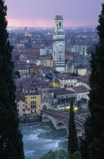 ITALY, Veneto, Verona, "Cityscape at sunset showing tiled rooftops, Duomo bell tower and bridge