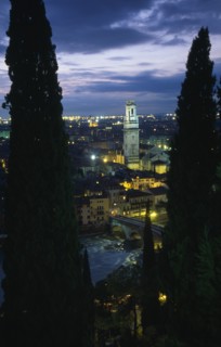 ITALY, Veneto, Verona, "Cityscape illuminated at night showing tiled rooftops, Duomo bell tower and