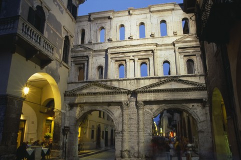 ITALY, Veneto, Verona, Street scene and Roman gateway at night with group of people framed in