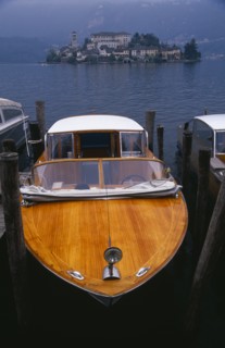 ITALY, Piedmont, Lake Orta, Moored boat taxi with small island densely covered with buildings