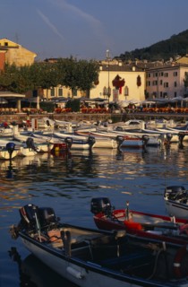 ITALY, Veneto, Lake Garda , Garda.  Harbour view with cafe tables set out on quayside overlooked by