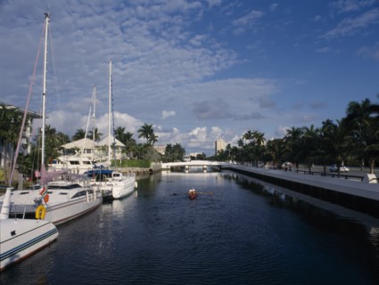 USA, Florida, Fort Lauderdale, Boats and waterside homes with a man traveling in a canoe on the