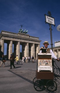 GERMANY, Berlin, Brandenburg Gate. Man in foreground under Pariser Platz sign performing with a