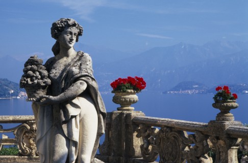 ITALY, Lombardy, Lake Como, Villa Balbianello.  Statue of woman holding basket of fruit with red