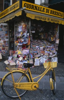 ITALY, Lombardy, Brescia, Piazza della Loggia.  Newspaper stand with yellow painted bicycle