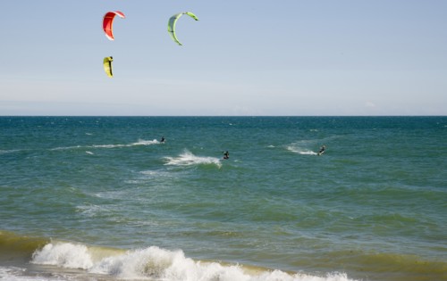 ENGLAND, West Sussex, Lancing, Kite Surfers on sea next to beach in the summer with blue sky