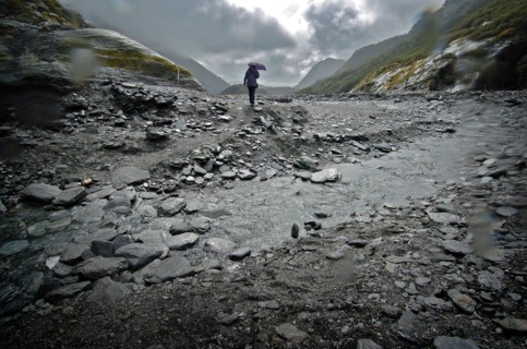 NEW ZEALAND, SOUTH ISLAND, WEST COAST, "MOUNT COOK NATIONAL PARK, A WALKER CROSSES A STREAM INFRONT