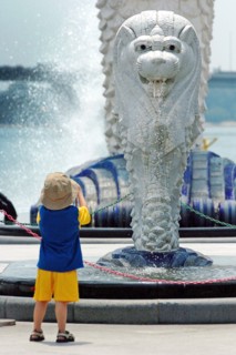 SINGAPORE, MARINA BAY, "A YOUNG BOY LOOKS ON AT A MINI VERSION OF THE MERLION STATUE. The Merlion