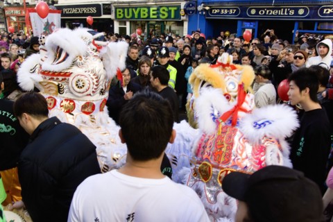 ENGLAND, London, Chinatown, Crowds passing under paper lanterns hung around one of the oriental