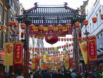 ENGLAND, London, Chinatown, Crowds passing under paper lanterns hung around one of the oriental