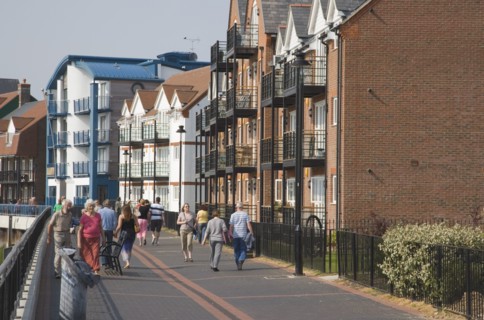 ENGLAND, West Sussex, Littlehampton, People walking along pathway next to the River Arun below
