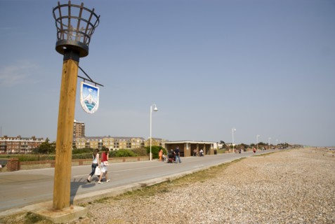 ENGLAND, West Sussex, Littlehampton, People walking along the promenade next to shingle beach with