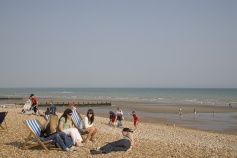 ENGLAND, West Sussex, Bognor Regis, A group of girls sitting on deck chairs on shingle beach with