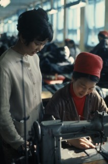 MONGOLIA, Work, Woman working at sewing machine in Ulan Bator tannery  leather factory with a young