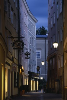 AUSTRIA, Salzburg, "Narrow street of Judengasse at night lined by tall, grey, pink and cream