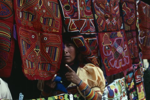 PANAMA, San Blas Islands, Kuna Indians, Kuna Indian woman looking out from between brightly
