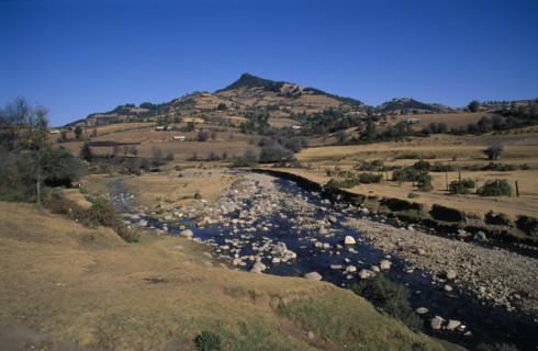 MEXICO, Michoacan State, El Rosario Butterfly Santuary, View across farmland and stream toward the