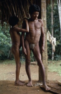 COLOMBIA, North West Amazon, Vaupes, Middle aged Maku nomad standing with his son beside frame of