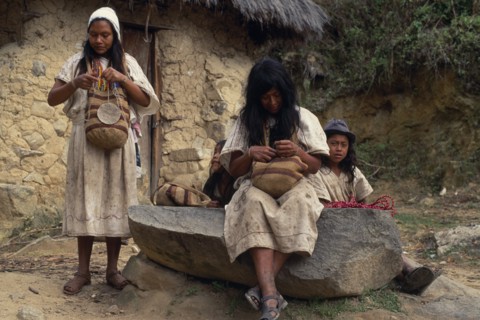 COLOMBIA, Sierra Nevada de Santa Marta, Ika, Ika women outside mud wattle thatched home sewing