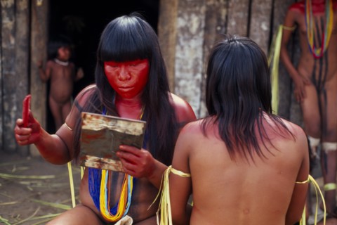 BRAZIL, Mato Grosso, Indigenous Park of the Xingu, Young Panara women applying red karajuru face