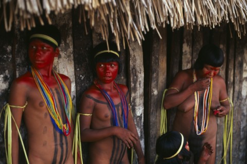 BRAZIL, Mato Grosso, Indigenous Park of the Xingu, Young Panara women applying red karajuru face