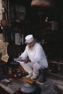 BOSNIA & HERZEGOVINA, Balkan Peninsula, Mostar, Elderly man wearing white sitting on step at