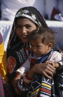 INDIA, Rajasthan, Bikaner, Kalbelia dancer woman holding her baby at the Camel Festival