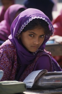INDIA, Rajasthan, Jhunjhunu, A young girl student dressed in purple sitting at a desk with books at