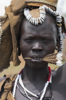 ETHIOPIA, South Omo Valley, Mursi Tribe, Portrait of woman with feather in her mouth.