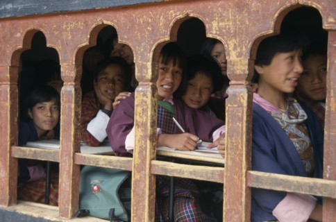 BHUTAN, Thimphu, "School children in class writing at desks framed in line of low set, arched,