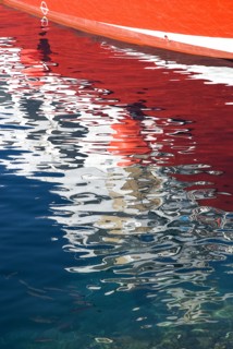 SPAIN, Canary  Islands, Lanzarote, Reflection of red hull of boat in rippled waters of the harbour