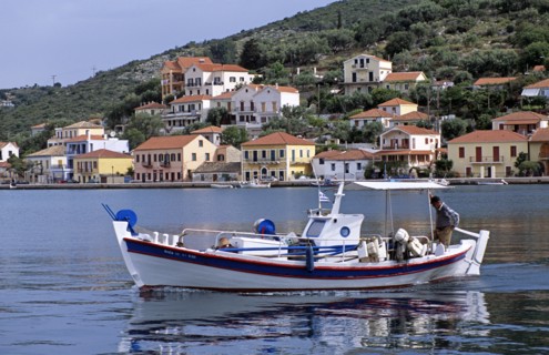 GREECE, Ionian Islands, Ithaca, Vathi. Boat moving in harbour and Vathi town behind.