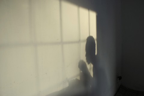 GAMBIA, Western Gambia, Tanji, Tanji Village.  Shadow of man eating and window frame on wall of