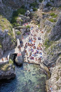 ITALY, Puglia, Lecce, Tricase.  Looking down on people sunbathing on coloured beach towels laid out