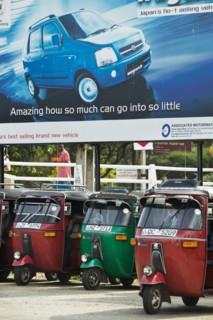 20091062 Tuk Tuks parked underneath advertising billboard Suzuki WagonR. Asia Asian Llankai Sri Lankan  Region - AsiaTransportMedia & CommunicationsDominant RedDominant Blue Jon Hicks 20091062 SRI...
