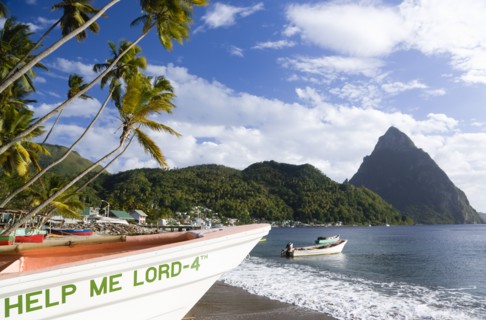 WEST INDIES, St Lucia, Soufriere, Fishing boats on the beach lined with coconut palm trees with the