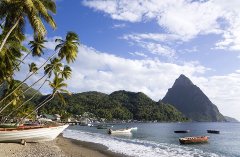 WEST INDIES, St Lucia, Soufriere, Fishing boats on the beach lined with coconut palm trees with the