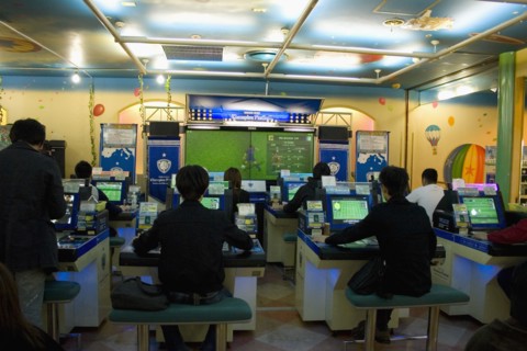 JAPAN, Honshu, Tokyo, Shinjuku.  Young Japanese seated in front of computer screens soccer video