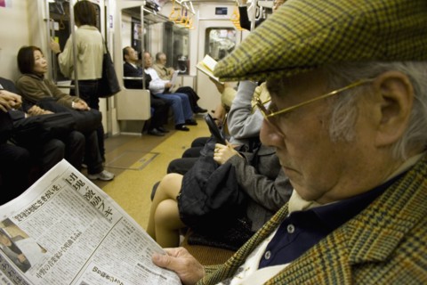 JAPAN, Honshu, Tokyo, Tokyo Metro.  Elderly Japanese man wearing tweed cap and jacket reading a