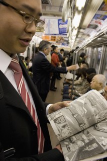 JAPAN, Honshu, Tokyo, Young Japanese man wearing a suit showing the Manga comic he is reading to